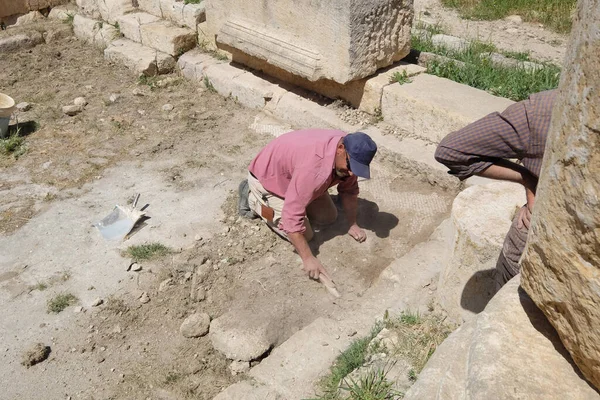 労働者はヨルダンのヤラシュの町の廃墟の上に地面を削り取る ヤラシュはローマとビザンツの遺跡で知られている 興味深いローマのサイト そして主要な観光客の絵カード — ストック写真