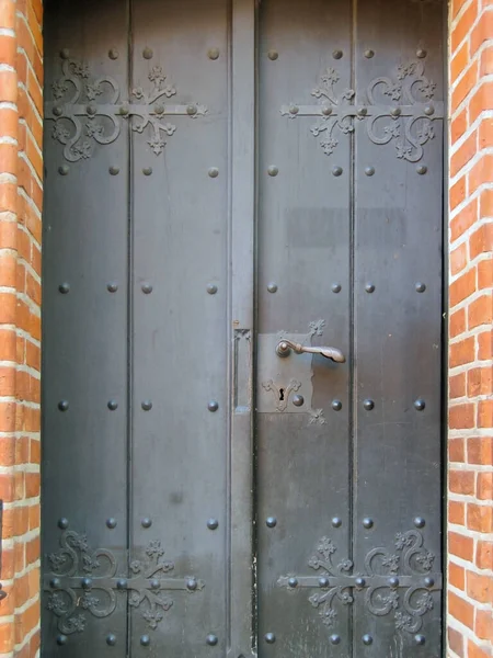 Brązowe Drewniane Drzwi Wykonane Nitowanych Desek Kręconymi Nakładkami Kutego Żelaza — Zdjęcie stockowe