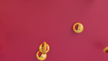 Kırmızı arka plana düşen bir grup sarı gülen emoji hapının 3 boyutlu animasyonu. 4k video.