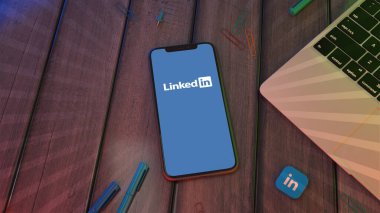 Tahta bir masaüstünde Linkedin uygulamasının logosunu gösteren bir akıllı telefonun 3B görüntülemesi