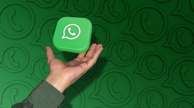 Kare bir Wharsapp rozeti yeşil arka planda bir erkeğin eline düşüyor..