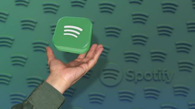 Odaklanmamış yeşil arka planda bir erkeğin eline düşen kare bir Spotify rozeti..