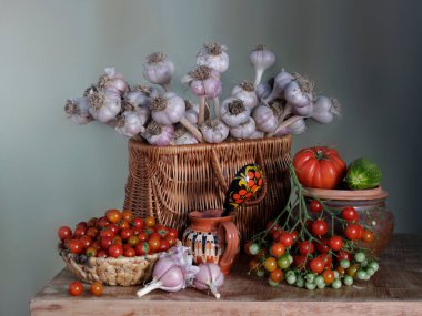 Sepette güzel bir buket sarımsak ve kırmızı domatesle sakin bir hayat. Masada zengin bir sarımsak ve domates hasadı var..