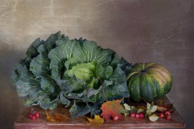 Muhteşem bir baş lahana, balkabağı, sonbahar yaprakları, kırmızı elmalar masada güzel bir şekilde yatıyor..