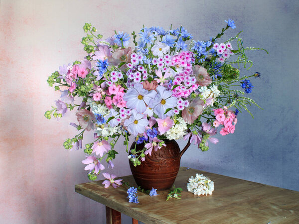 A magnificent bouquet with herbs and blue and pink in a vase on the table.