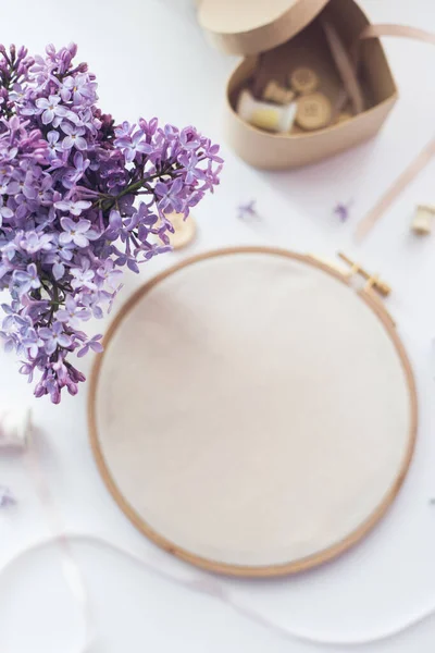 Flach liegendes Draufsicht-Foto einer Attrappe mit Stickrahmen und Lila-Blumen. — Stockfoto