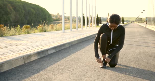 Afroamericana en forma mujer atando cordones al aire libre — Vídeos de Stock