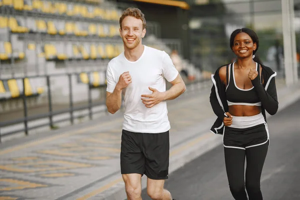 African-american woman and caucasian man jogging at the stadium