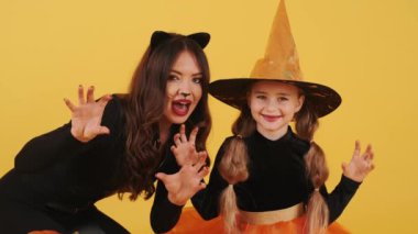 Cadılar Bayramı kostümü giyen anne ve kızı turuncu stüdyodalar.