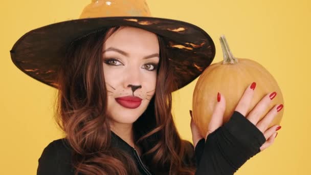 Kobieta w halloween makijaż gospodarstwa pompowanie na pomarańczowym tle — Wideo stockowe