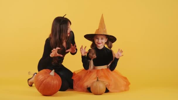 Mère et fille portant des costumes d'Halloween ont en studio orange — Video
