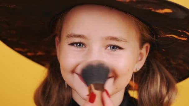 Kvinne applyndre sminke på jenter ansikt på oransje bakgrunn – stockvideo
