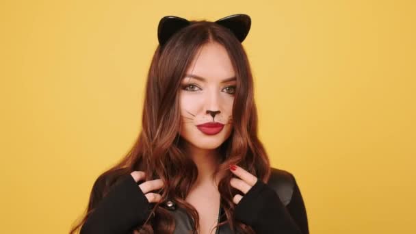 Hübsche junge Frau im Katzenkostüm bereitet sich in einem orangefarbenen Studio vor — Stockvideo