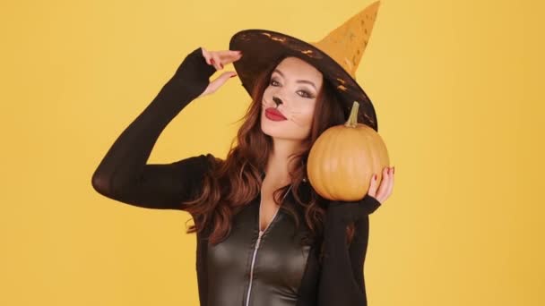 Frau in Halloween-Make-up hält Pumpking auf orangefarbenem Hintergrund — Stockvideo