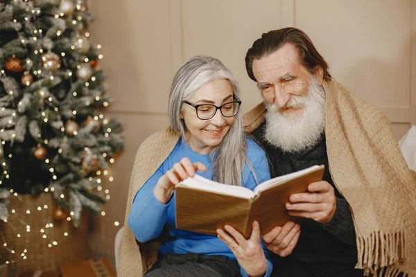 Senior couple with book near the Christmas tree