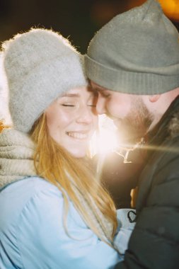 Kış tatili gebeliği. Genç bir çiftin açık hava gece portresi. Avrupa sokaklarında poz vermek.