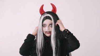 Korkunç kötü kostümlü çocuk beyaz arka planda somurtuyor.