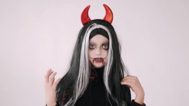 Korkunç kötü kostümlü çocuk beyaz arka planda somurtuyor.