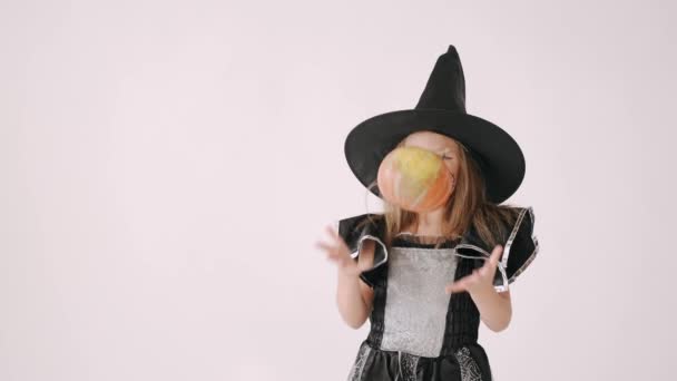 Portret van meisje in een zwarte hoed en zwarte kleding met pompoen op witte achtergrond — Stockvideo