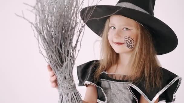Portret van meisje in een zwarte hoed en zwarte kleding met bezem op witte achtergrond — Stockvideo