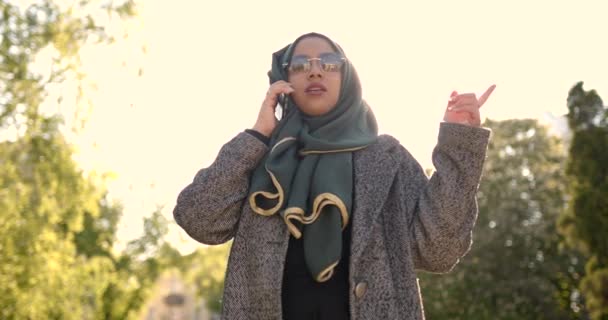 Мусульманка в вуали разговаривает по телефону на улице — стоковое видео