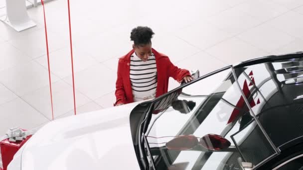 Африканська американка вибирає автомобіль у салоні і перевіряє салон. — стокове відео