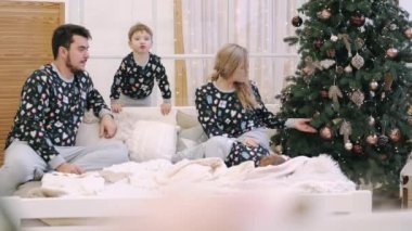 Mutlu ebeveynler ve çocuklar evde Noel ağacının yanında eğleniyor.