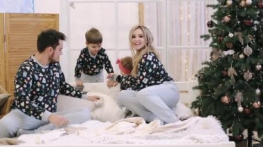 Mutlu ebeveynler ve çocuklar evde Noel ağacının yanında eğleniyor.