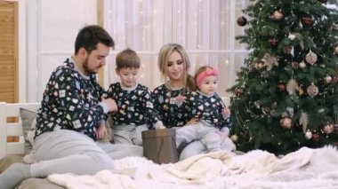 Noel ağacının yanında açılan dört noel hediyesinin ailesi