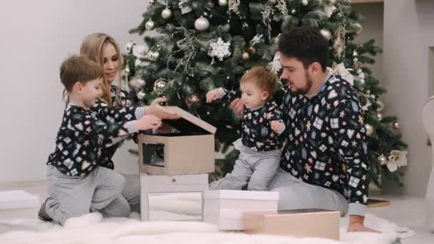 Famille de quatre cadeaux de Noël déballage près de l'arbre de Noël — Video