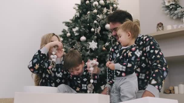 Famille de quatre cadeaux de Noël déballage près de l'arbre de Noël — Video