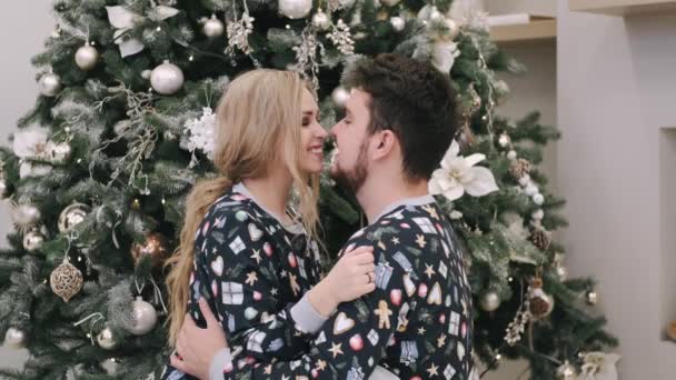 Atraente alegre homem e mulher sentado perto de árvore de natal abraço — Vídeo de Stock