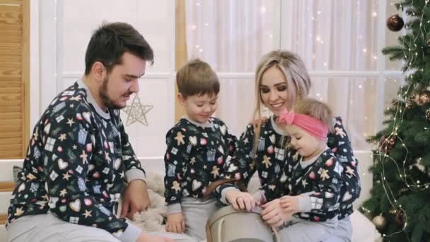 Familia de cuatro regalos de Navidad cerca del árbol de Navidad — Vídeo de stock