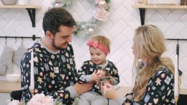 Sıcak süveter giyen genç bir aile ve Noel odasında bir kız çocuğu.