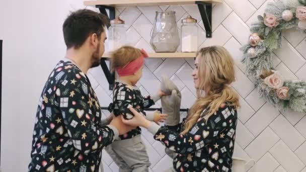Una familia joven en suéteres cálidos con una hija pequeña en un dormitorio de Navidad — Vídeos de Stock