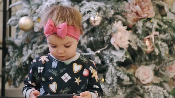 Belle petite fille mignonne utiliser smartphone assis près de l'arbre de Noël — Video