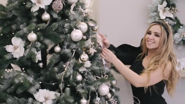 Young beutifully dresse woman decorate christmas tree at home — Stock Video