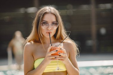 Havuzda kokteyl içen güzel bir kadın.