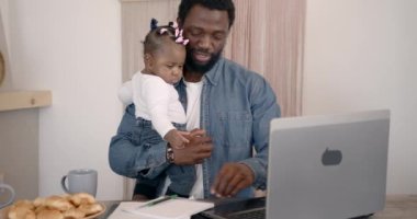 Kahvaltı sırasında dizüstü bilgisayar kullanan genç bir aile