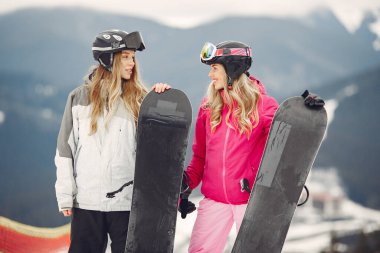 Dağlarda snowboard yapan kızlar.