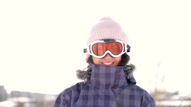 Kvinna snowboardåkare sätta på goggles på skidorten innan skidåkning — Stockvideo