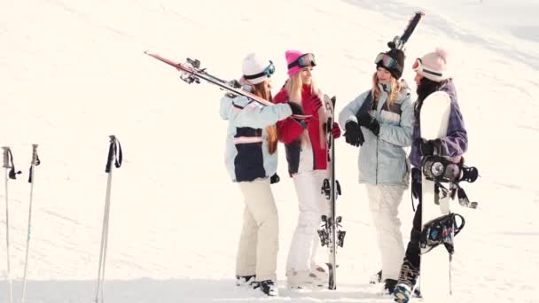 Mujeres snowboarders y esquiadoras en la ladera de la montaña hablando y relajándose después de deslizarse — Vídeo de stock