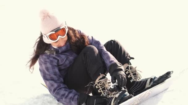 Mujer snowboarder pone en una tabla de snowboard de cerca — Vídeo de stock