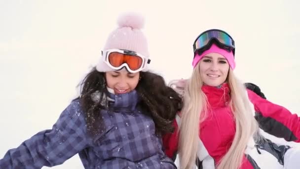 Két gyönyörű, nevető fiatal nő a sípályán — Stock videók