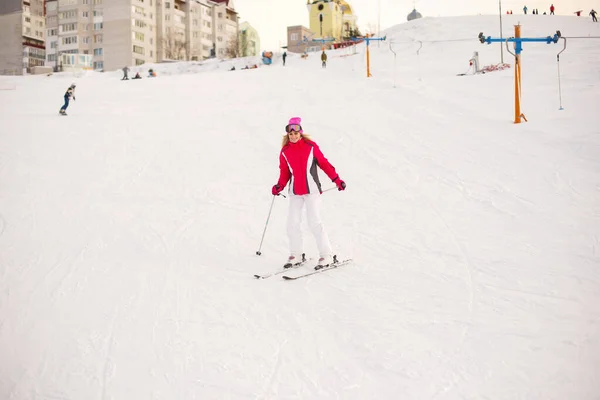 Flicka skidåkning i berg i en rosa och vit skiddräkt — Stockfoto