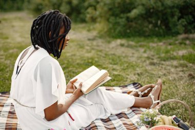 Afrikalı bir kız piknikte kitapla rahatlıyor.