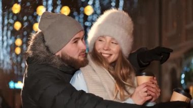 Şehirde genç bir çift Noel zamanı sıcak kahve içer.