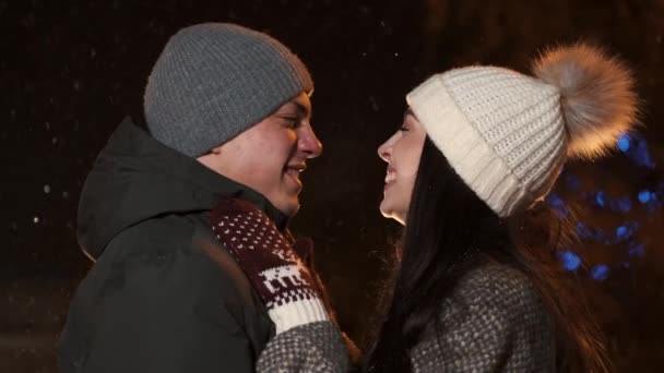 夜間休日の冬のイルミネーションの下の若いカップルのキスします。 — ストック動画