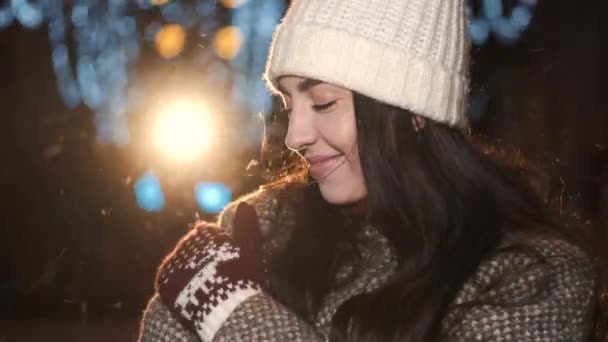美丽的年轻女子头戴帽子，身穿外套，站在圣诞节的夜晚 — 图库视频影像