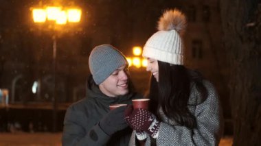 İki sevgi dolu insan ellerindeki sıcak içecekle birlikte Noel akşamını birlikte geçirirler.